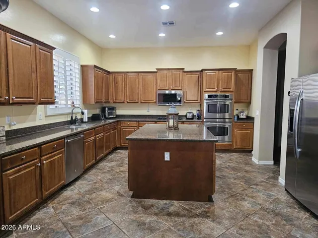 a kitchen with stainless steel appliances granite countertop a stove a sink a refrigerator and a refrigerator