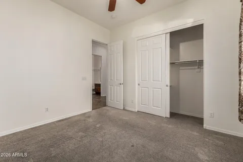 an empty room with chandelier fan and windows