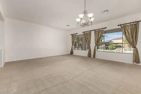 a view of an empty room with chandelier fan and wooden floor