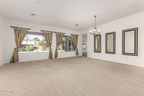 a view of an empty room with large windows and chandelier