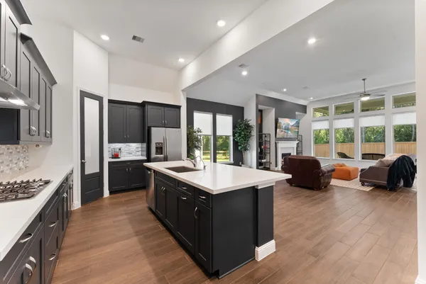 a kitchen with kitchen island granite countertop a stove and a view of living room