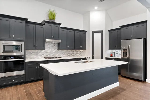a kitchen with stainless steel appliances kitchen island granite countertop a refrigerator and a stove