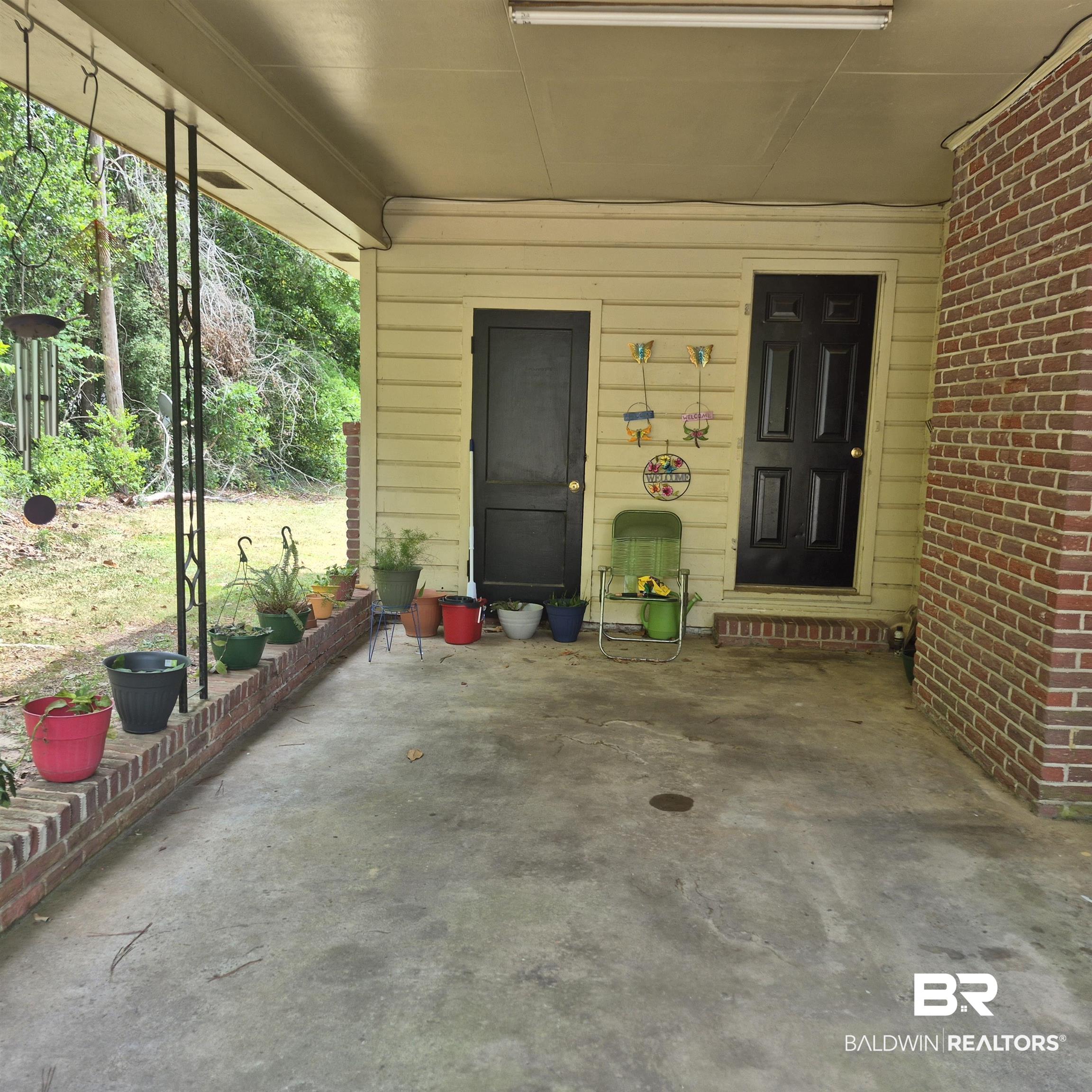 108 Azalea Street Evergreen, AL 36401 - Photo 4 of 19 Covered concrete patio with two black panel doors