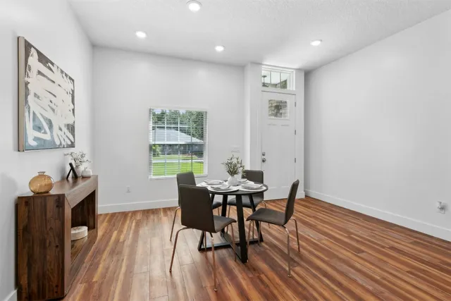 a kitchen with stainless steel appliances granite countertop a refrigerator a sink dishwasher a stove and a dining table with wooden floor