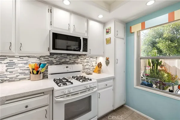 a kitchen with granite countertop a stove a sink and a microwave