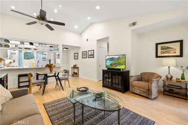 a living room with furniture and a flat screen tv with kitchen view