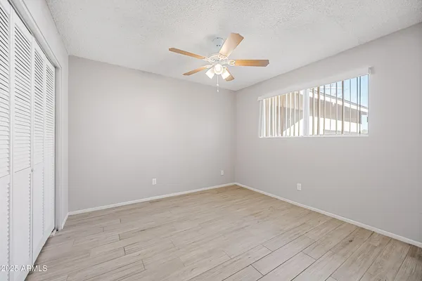 an empty room with wooden floor fan and windows