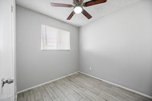 an empty room with a window and a chandelier fan