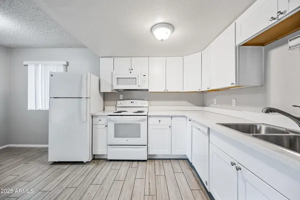 a kitchen with cabinets appliances wooden floor and a window