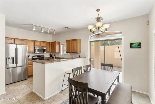 a kitchen with stainless steel appliances granite countertop a refrigerator a sink dishwasher a dining table and chairs with wooden floor