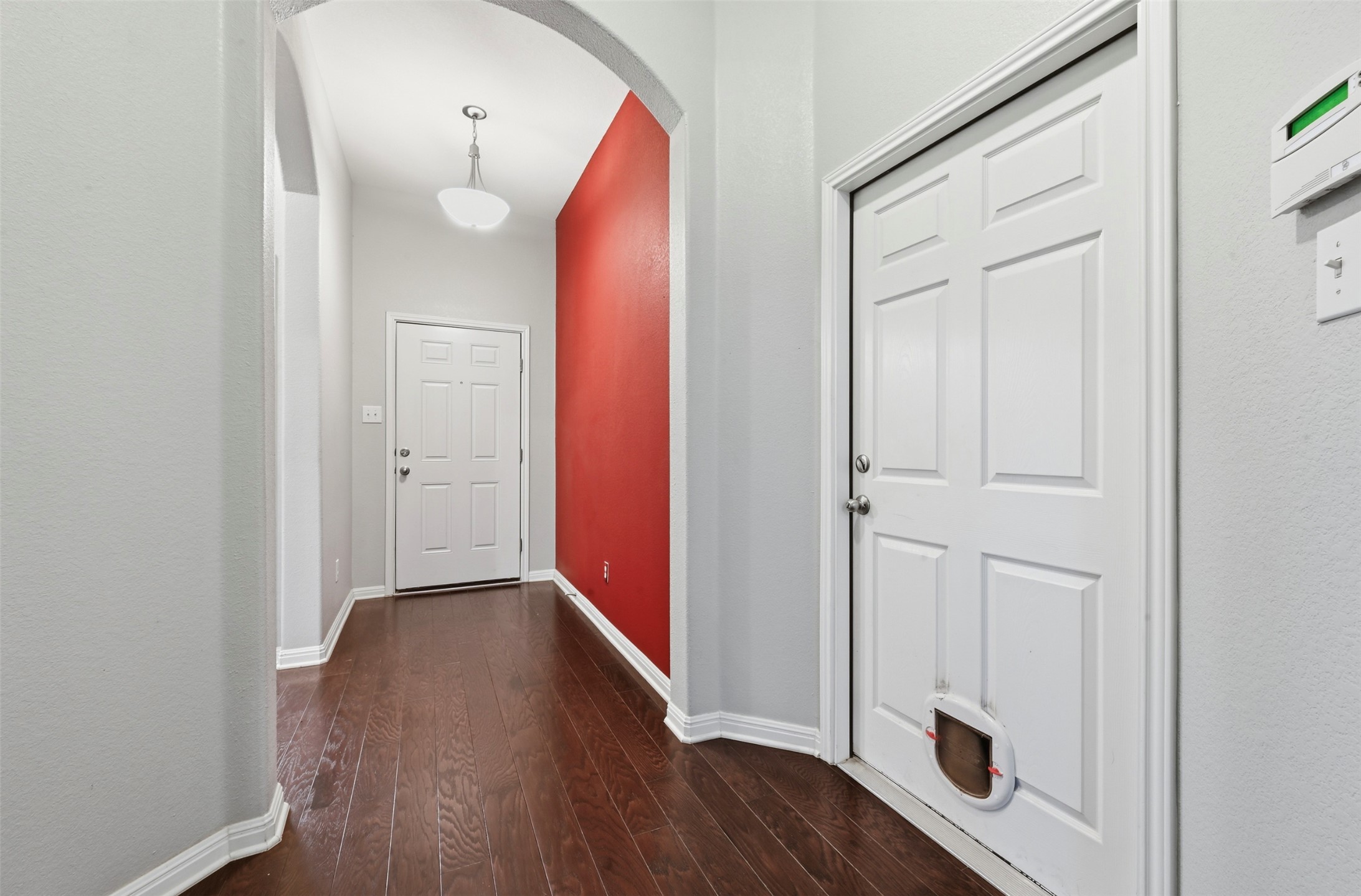 13116 Alans Way Manchaca, TX 78652 - Photo 4 of 25 Hallway featuring wood-finish flooring, an arched entryway, and a red accent wall