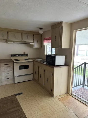 a kitchen with granite countertop a stove a sink and a refrigerator