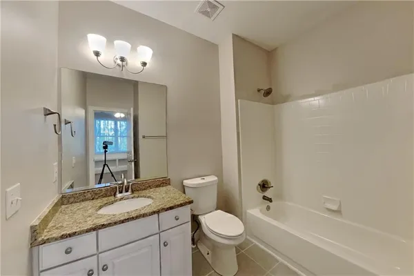 a bathroom with a granite countertop sink a toilet and bathtub