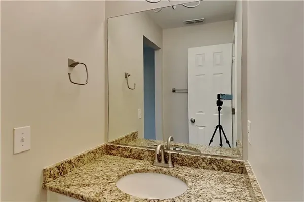 a bathroom with a granite countertop sink and a mirror