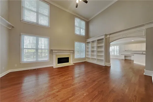 an empty room with wooden floor fireplace and windows