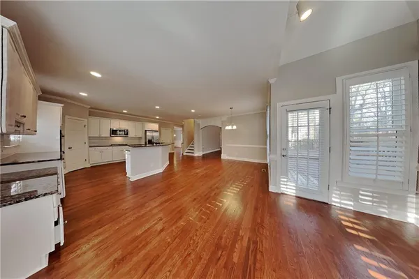 a room with stainless steel appliances wooden floors and kitchen view