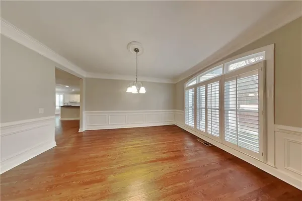 a view of an empty room with window and wooden floor