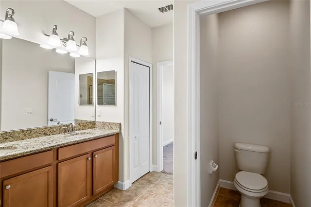 a bathroom with a granite countertop sink a toilet and a mirror