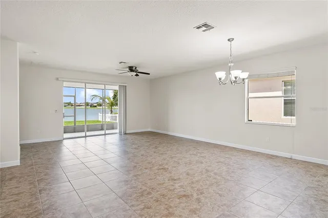 an empty room with chandelier and windows