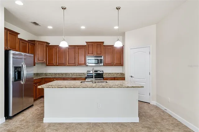 a large kitchen with stainless steel appliances granite countertop a sink a stove and a refrigerator