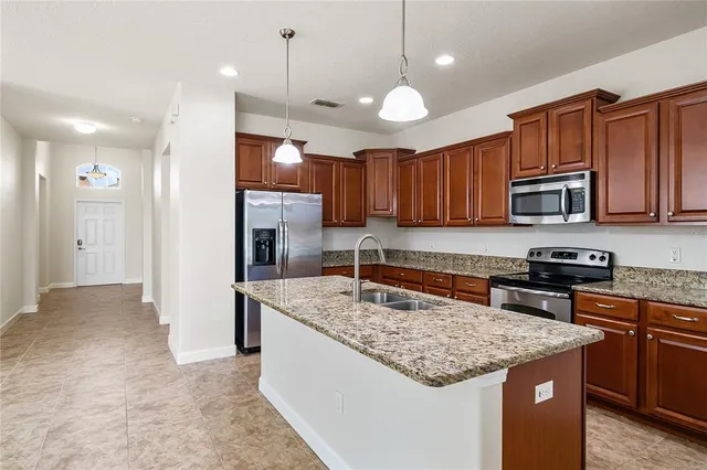 a kitchen with kitchen island granite countertop wooden cabinets a stove a sink and a oven