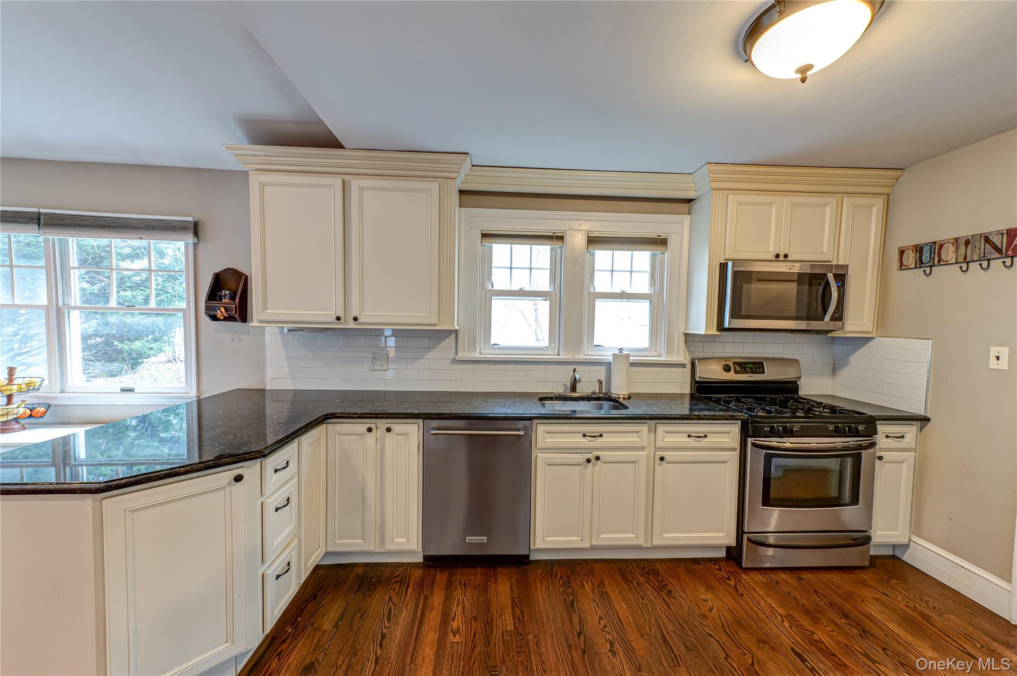 75 Bar Beach Road Port Washington, NY 11050 - Photo 16 of 30 a white kitchen with wooden floor and stainless steel appliances