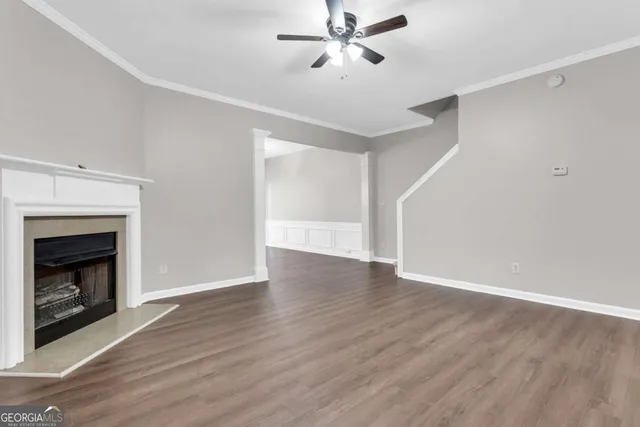 a view of an empty room with wooden floor fireplace and a window