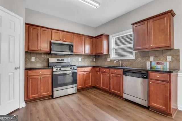 a kitchen with stainless steel appliances granite countertop wooden cabinets a stove a sink and a window