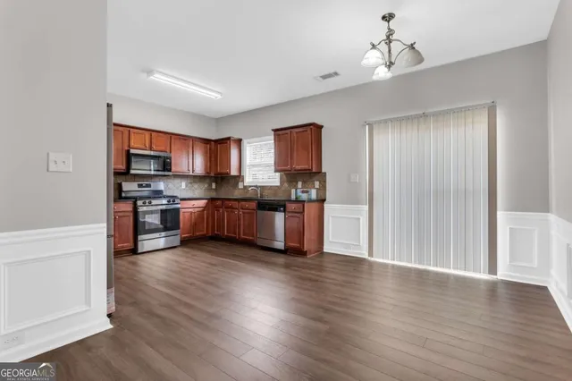 a kitchen with stainless steel appliances granite countertop a stove top oven a sink and dishwasher with wooden floor