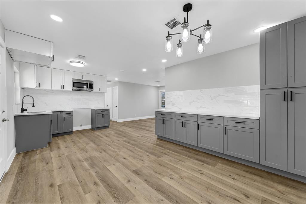 a large white kitchen with a white wooden cabinets and chandelier