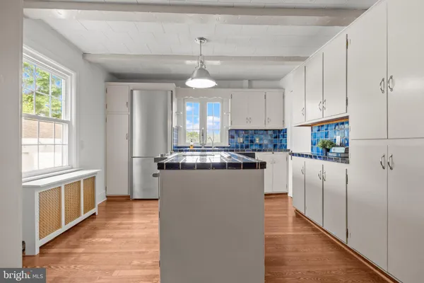 a kitchen with stainless steel appliances granite countertop a refrigerator a sink dishwasher a oven and white cabinets with wooden floor