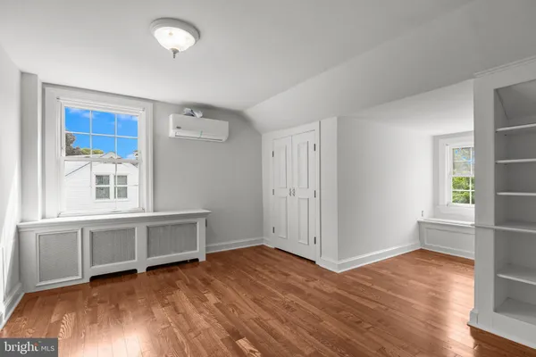an empty room with wooden floor cabinet and windows