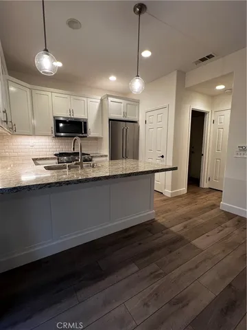 a kitchen with kitchen island granite countertop a sink cabinets and stainless steel appliances