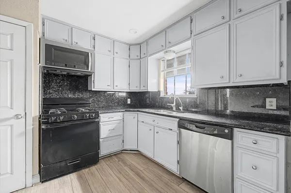 a kitchen with granite countertop white cabinets and stainless steel appliances