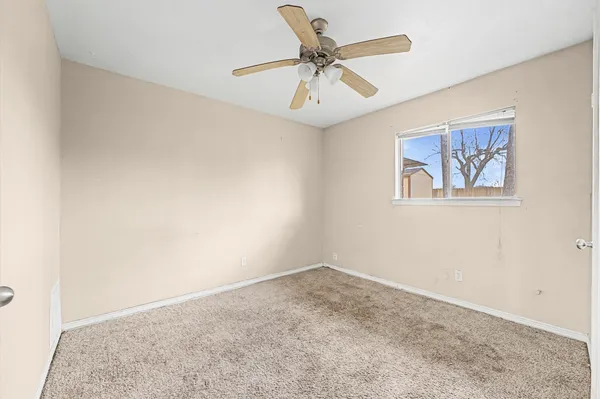 an empty room with a window and a ceiling fan