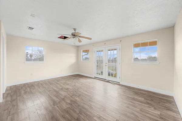 a view of an empty room with a window and wooden floor