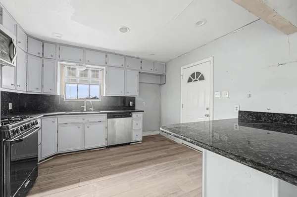 a kitchen with granite countertop a sink stainless steel appliances and white cabinets