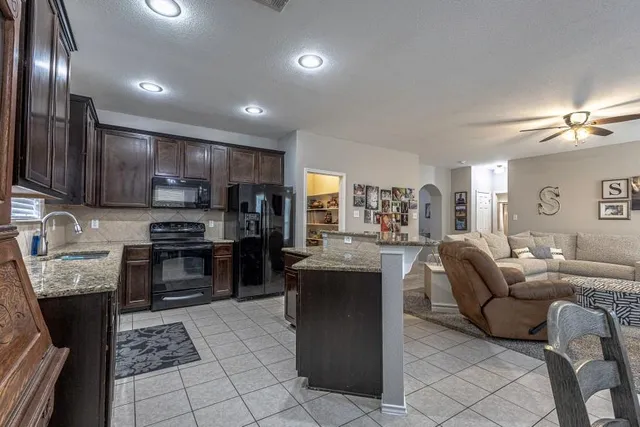 a living room with furniture a kitchen view and a chandelier