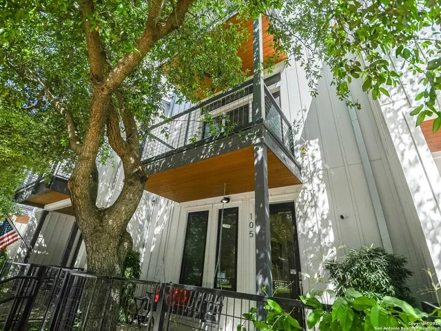 a view of a house with a small yard and large tree