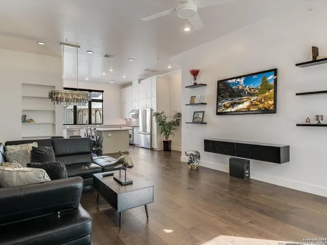 a living room with furniture and kitchen view with wooden floor