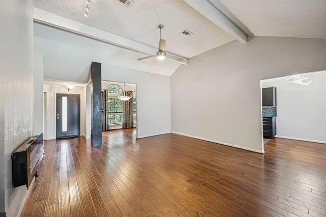 a view of an empty room with wooden floor and a window