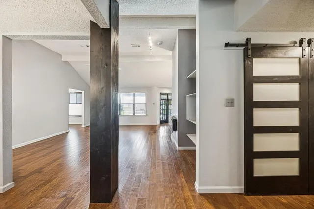 a view of an empty room with a window and wooden floor