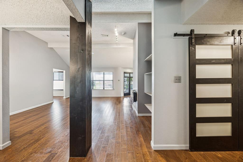405 Rose Drive Allen, TX 75002 - Photo 6 of 31 As you step inside 405 Rose Drive, notice the beautiful flooring that runs throughout much of the home. Find the utility space through the charming barn doors shown to the right of the photo. (Note:Property is occupied but shown vacant)