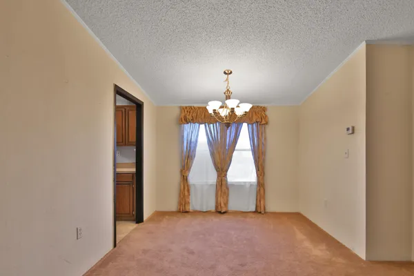 an empty room with chandelier fan and windows