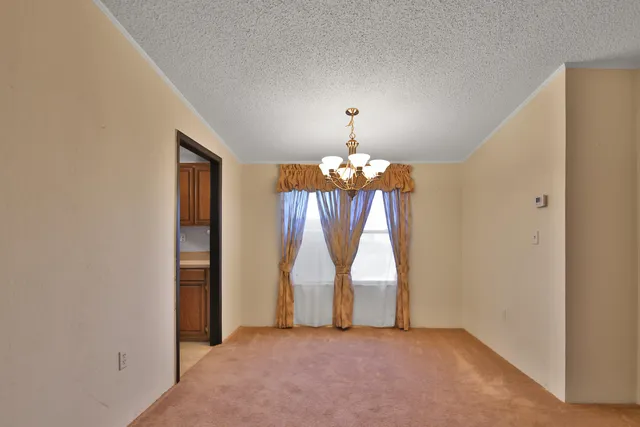 an empty room with chandelier fan and windows
