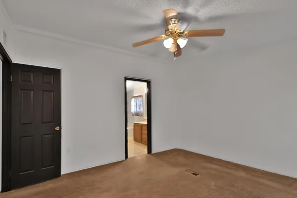 an empty room with windows mirror and fan