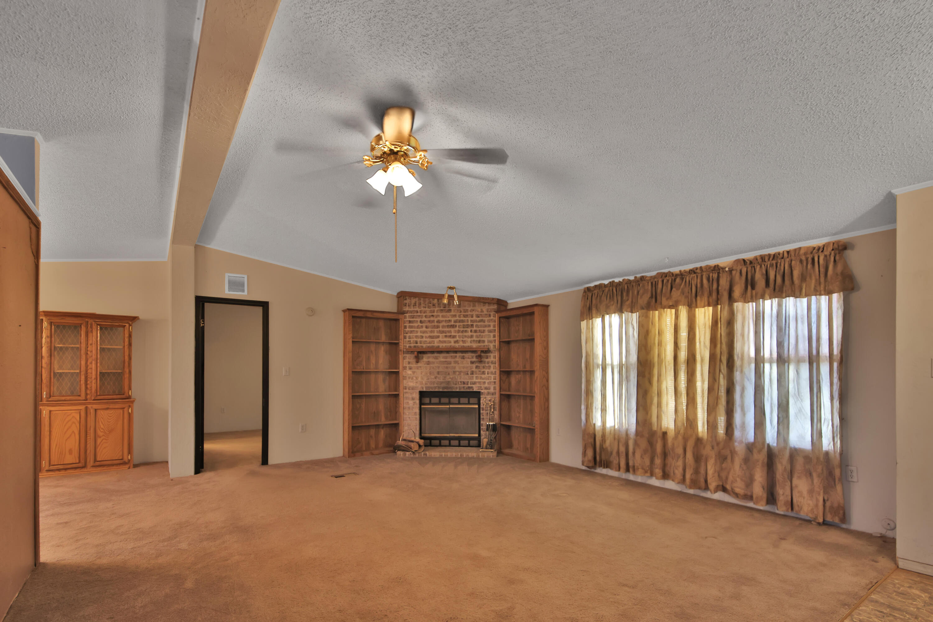 120 Highway 114 Estates Road Lubbock, TX 79407 - Photo 27 of 49 an empty room with a fireplace and a ceiling fan