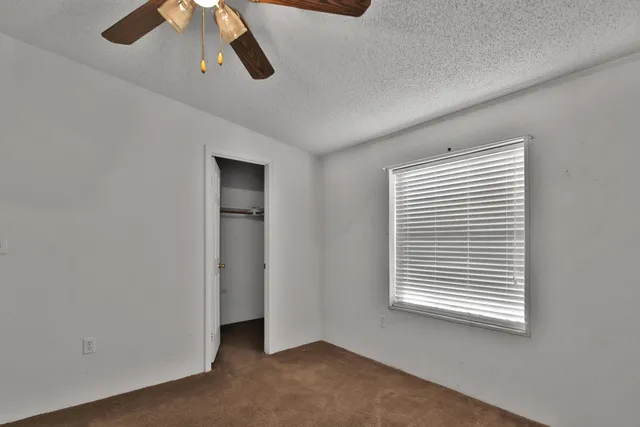 an empty room with closet and a chandelier fan