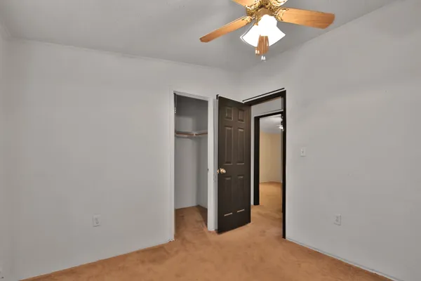 an empty room with closet and a chandelier fan