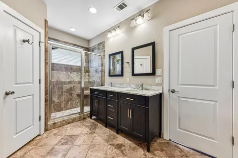 a bathroom with a granite countertop sink mirror and a shower